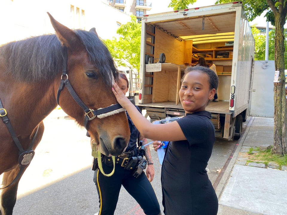 Student petting police horse in front of the school during career day.