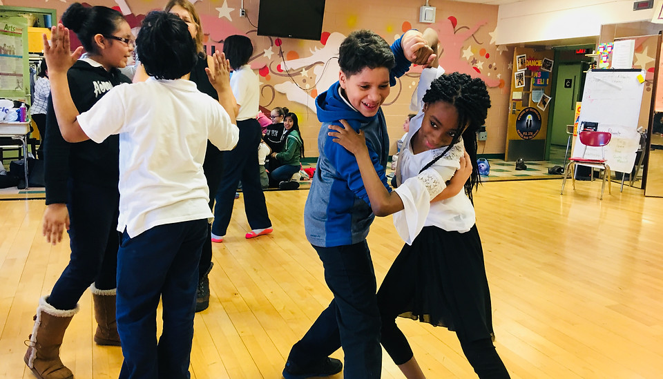 Students engaged in partner dance in the dance studio.